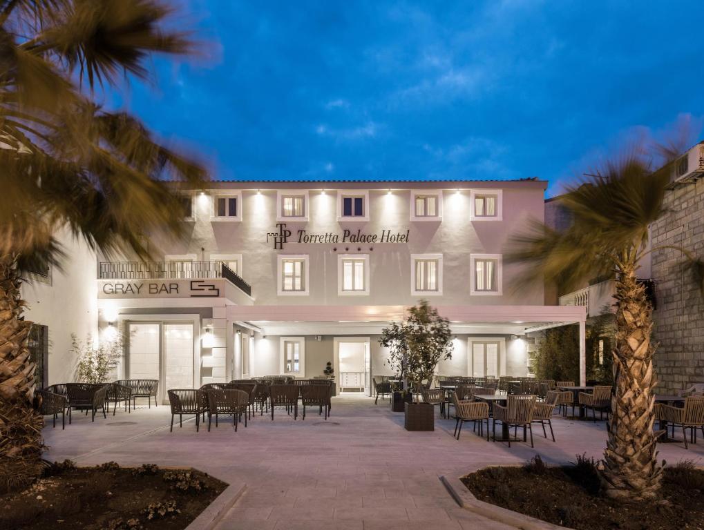 een groot gebouw met tafels en stoelen ervoor bij Torretta Palace Hotel in Turanj