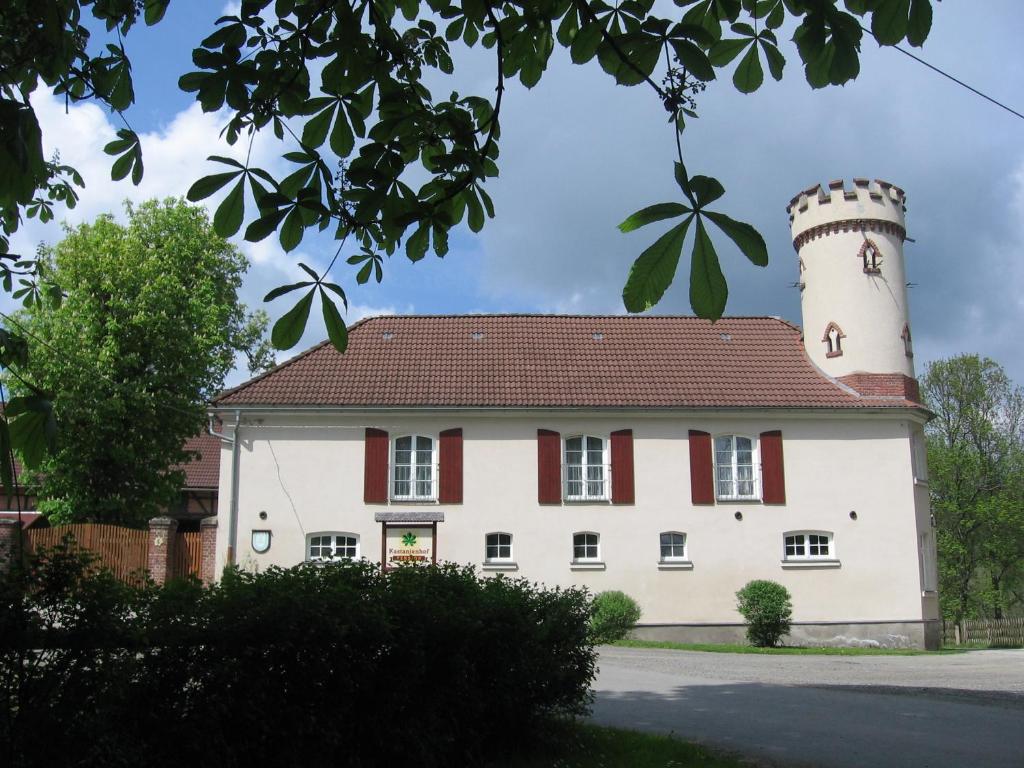 ein großes weißes Gebäude mit einem Turm in der Unterkunft Pension Kastanienhof in Zeulenroda