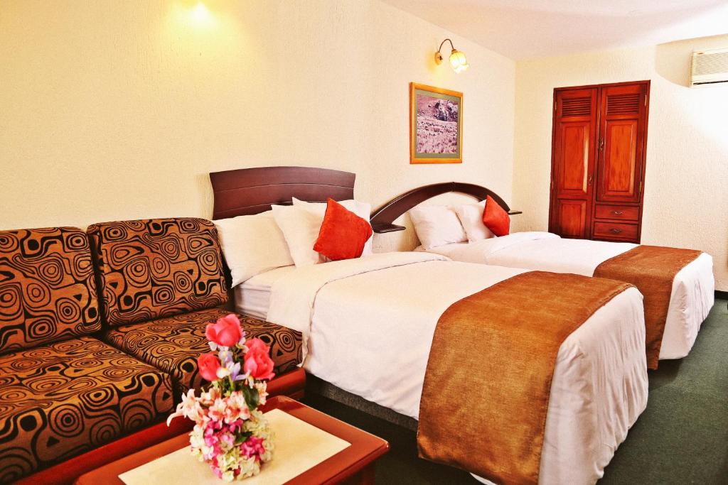 a hotel room with two beds and a couch at Apart Hotel Caminos del Inca in Lima