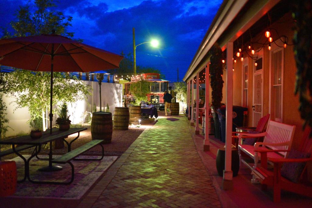 a patio with tables and chairs and an umbrella at night at Painted Lady Bed & Brew in Albuquerque