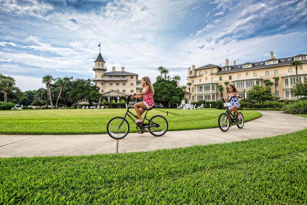 杰基尔岛Jekyll Island Club Resort的两个女孩在建筑物前骑自行车