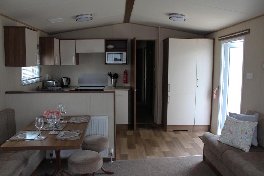 a living room with a table and a kitchen at 3 Bed Static Caravan @ Hoburne Devon Bay in Paignton