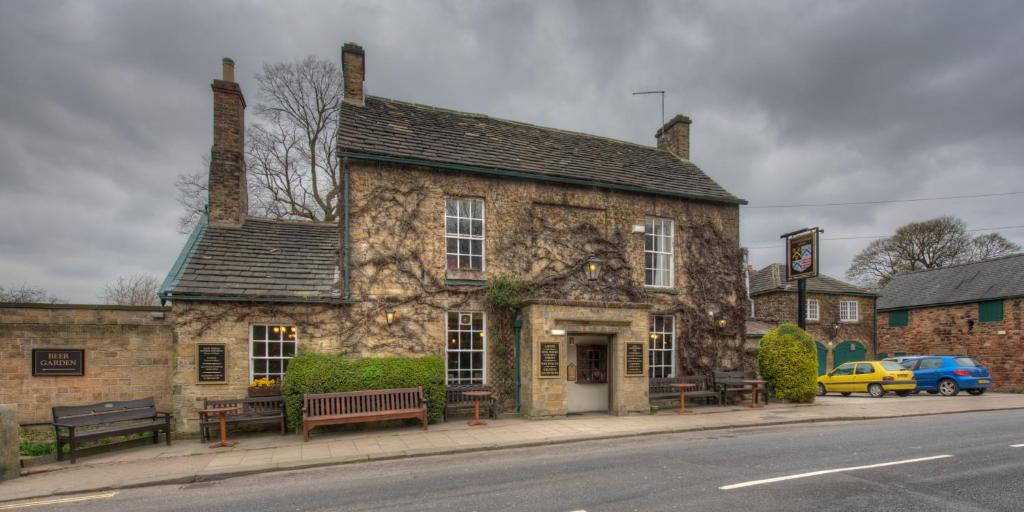 - un vieux bâtiment en pierre au coin d'une rue dans l'établissement Rockingham Arms By Greene King Inns, à Wentworth