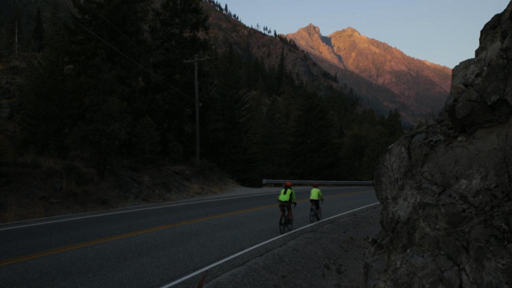 two people riding their bikes on a road at Sleeping Lady Mountain Resort in Leavenworth