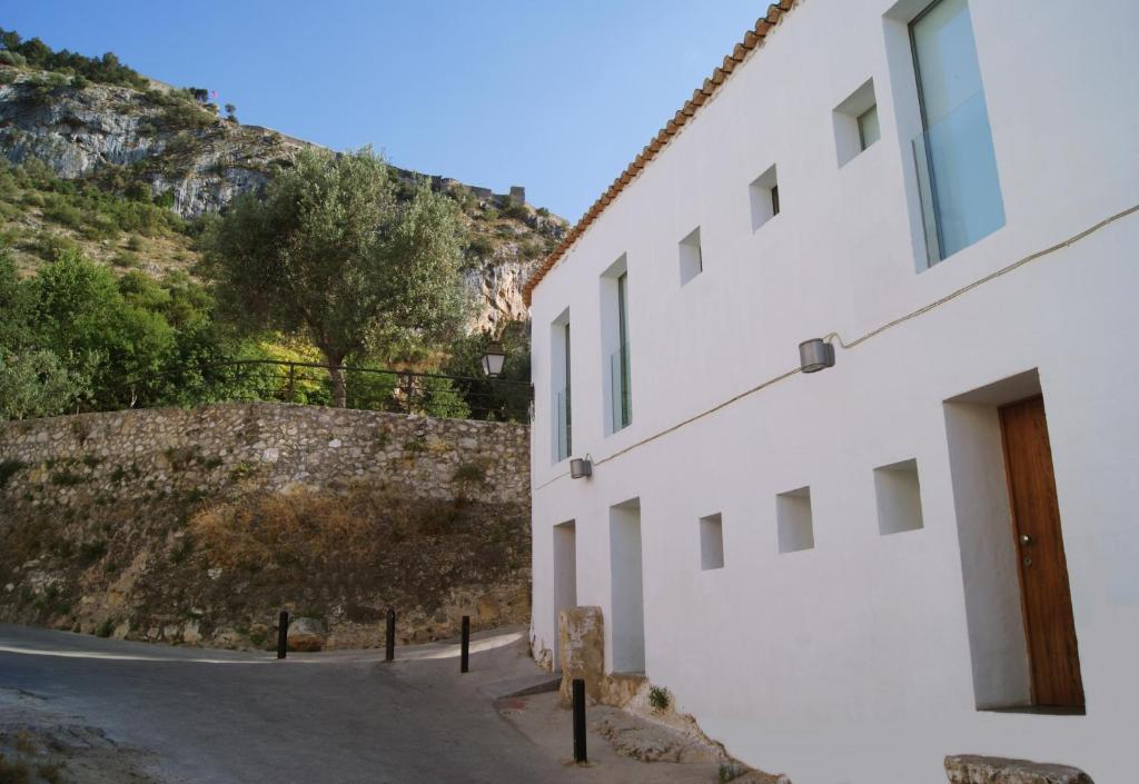 a white building next to a stone wall at La Maga Rooms in Xàtiva