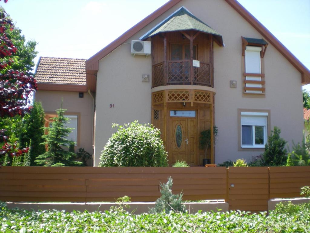 una casa con una puerta de madera y una valla en Xénia Apartmanok, en Hajdúszoboszló
