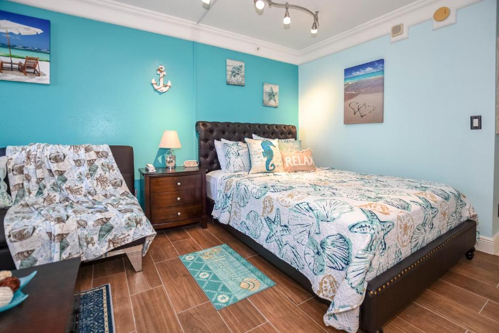 1 dormitorio con paredes azules, 1 cama y 1 silla en Ocean view studio condo. en Daytona Beach