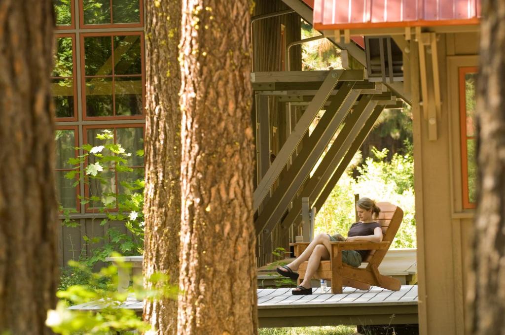 a woman sitting on a chair on the porch of a house at Sleeping Lady Mountain Resort in Leavenworth