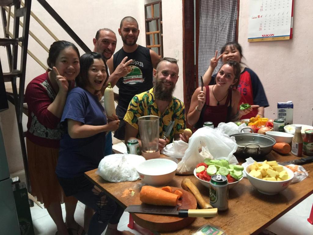 eine Gruppe von Menschen, die um einen Tisch mit Essen stehen in der Unterkunft Happy Homestay in Buon Ma Thuot