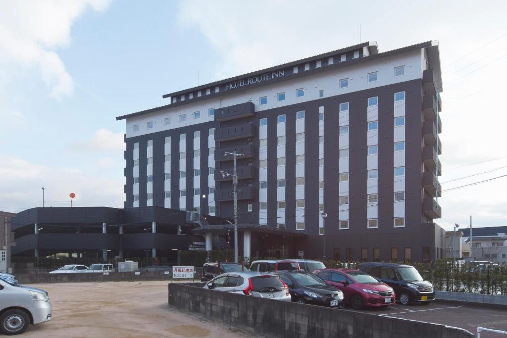 un gran edificio con coches estacionados en un estacionamiento en Hotel Route-inn Yamaguchi Yuda Onsen en Yamaguchi