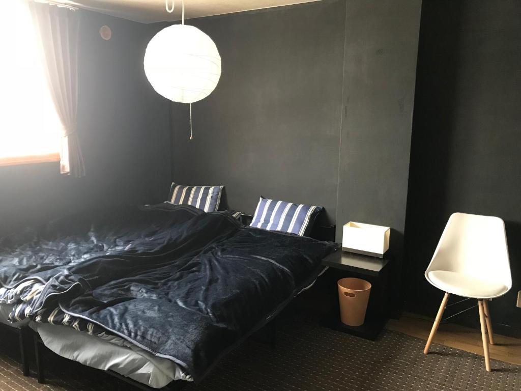 a bedroom with a black bed and a white chair at Hokkaido Bed & Bagel in Eniwa
