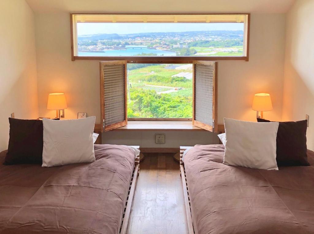 a bedroom with two beds and a large window at Kaiza in Nanjo