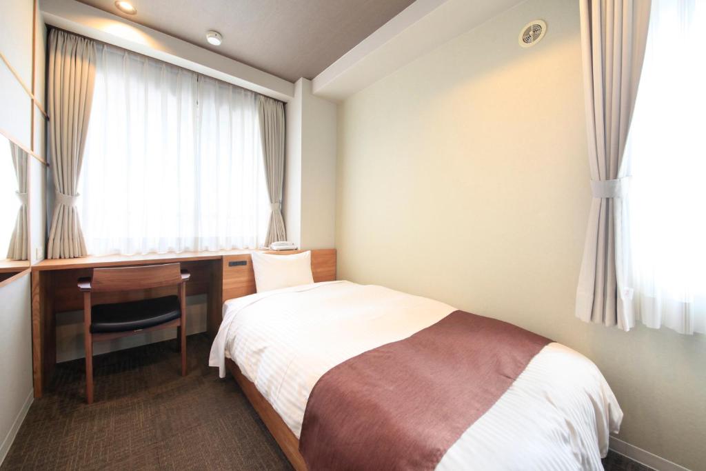 een slaapkamer met een bed, een bureau en een raam bij Posada Suimei in Hakone