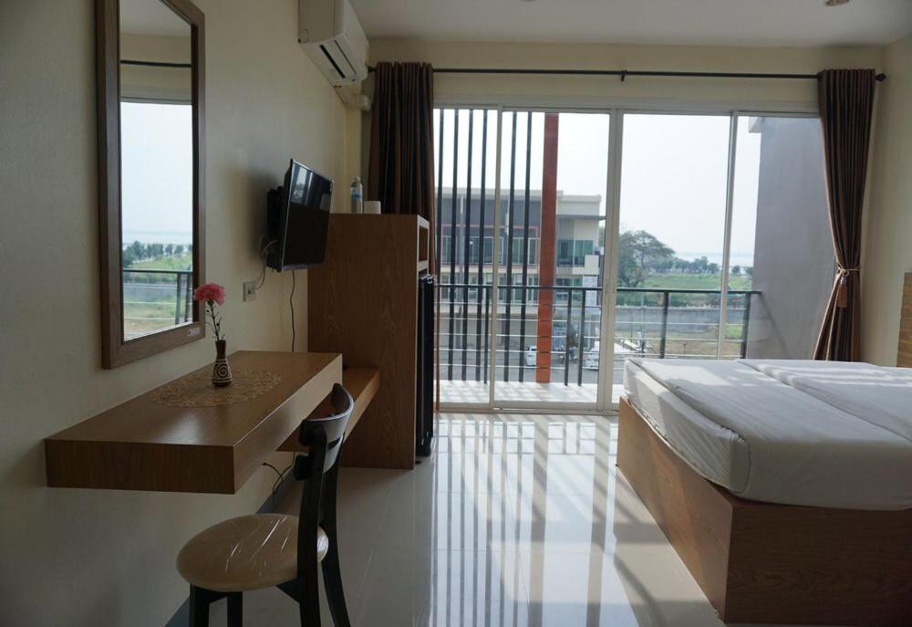 een slaapkamer met een bed, een bureau en een balkon bij Lew Residence in Phayao