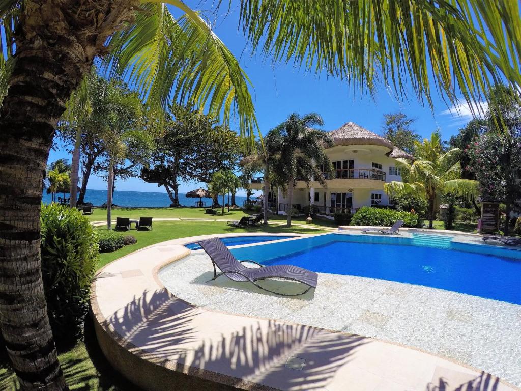 a villa with a swimming pool and a palm tree at Vida Homes Condo Resort in Dauin