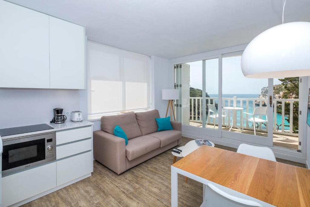 ein Wohnzimmer mit einem Sofa und einem Tisch in der Unterkunft Apartamentos Playa Canutells in Maó