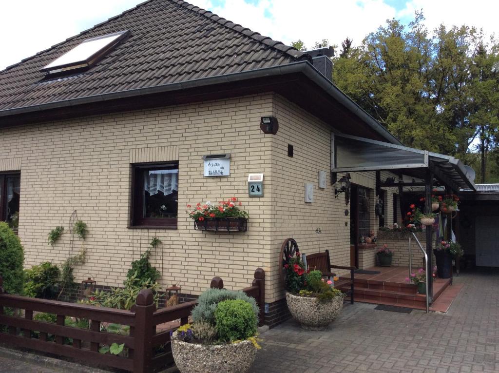 aige house with a porch and flowers in front of it at Ferienwohnung Waldblick in Munster im Heidekreis