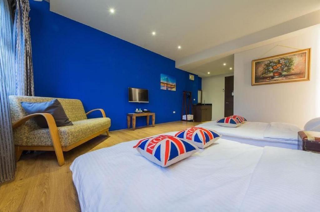 a bedroom with two beds and a blue wall at Ritual and Breakfast in Hualien City