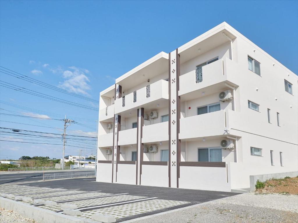 讀谷的住宿－Condominium・yuyuki，道路一侧的白色建筑