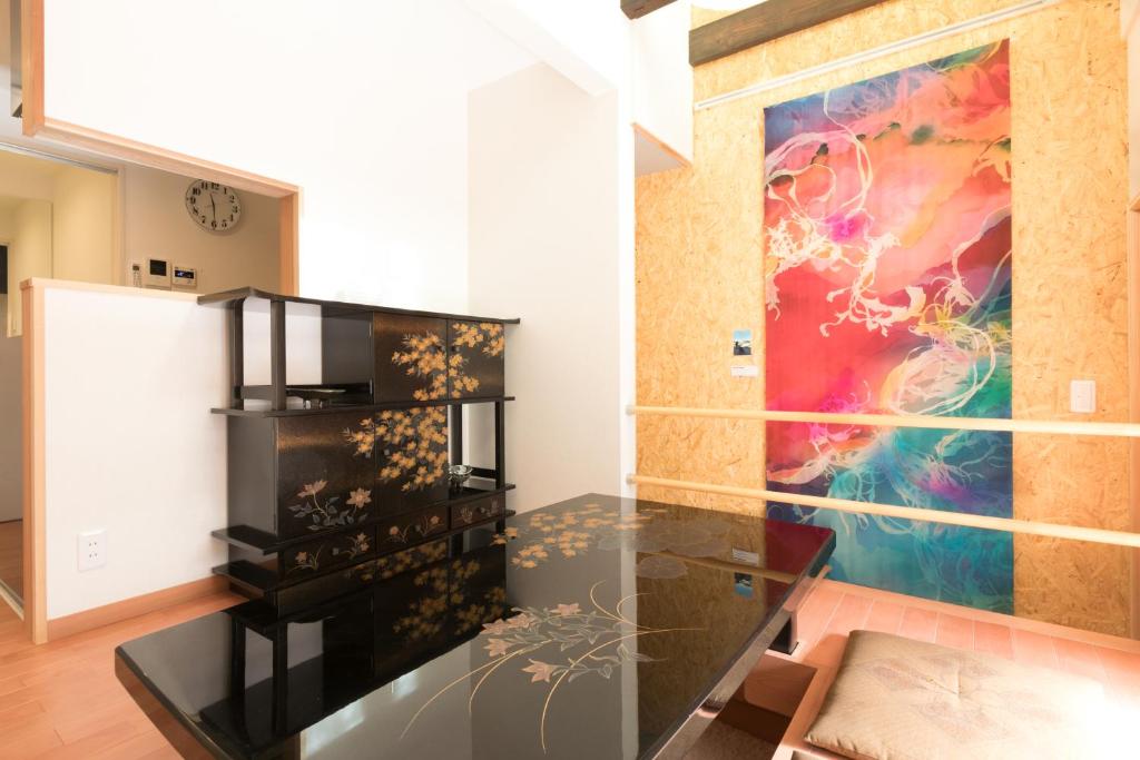 Zimmer mit einem Glastisch und einem Gemälde an der Wand in der Unterkunft Guesthouse Tonton Nobu in Kyoto
