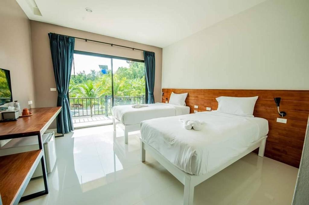 a bedroom with two beds and a desk and a window at Saithong Resort in Pak Meng