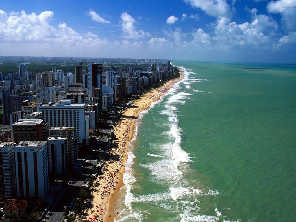 eine Luftansicht auf einen Strand mit Gebäuden und das Meer in der Unterkunft Apartamento Guaruja Bacaitava in Guarujá