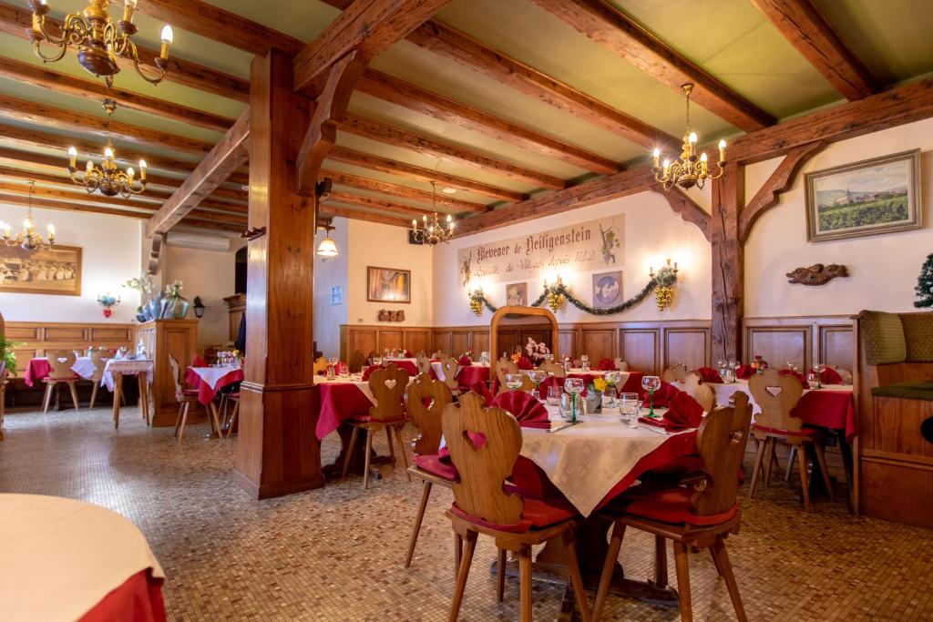 een eetkamer met tafels en stoelen en kroonluchters bij Relais du Klevener in Heiligenstein
