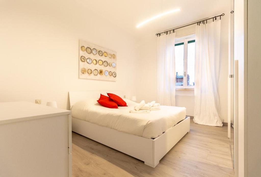 Dormitorio blanco con cama con almohadas rojas en YouHosty - Pantigliate 8, en Milán