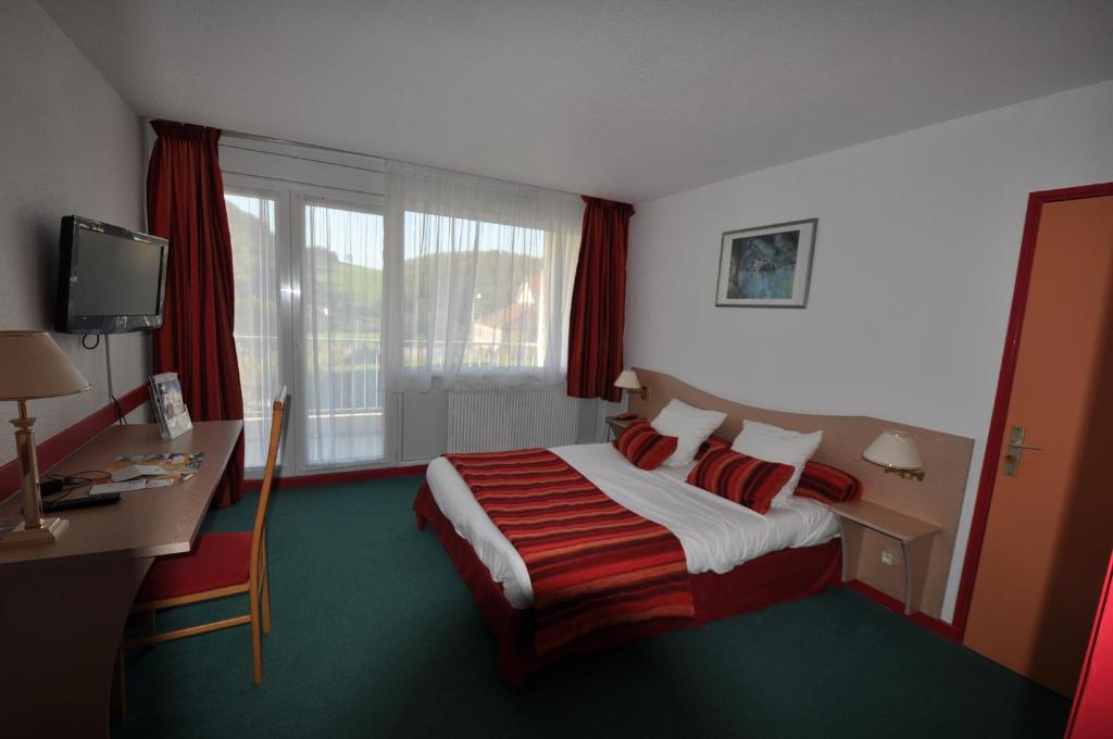 a hotel room with a bed and a desk and window at Le Relais De La Vallee in Hyèvre-Paroisse