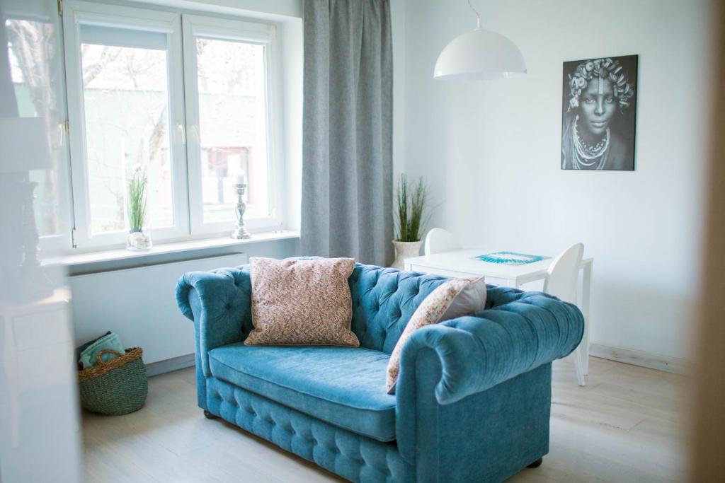 a blue couch in a living room with a window at Flat White Apartament Pułtusk in Pułtusk