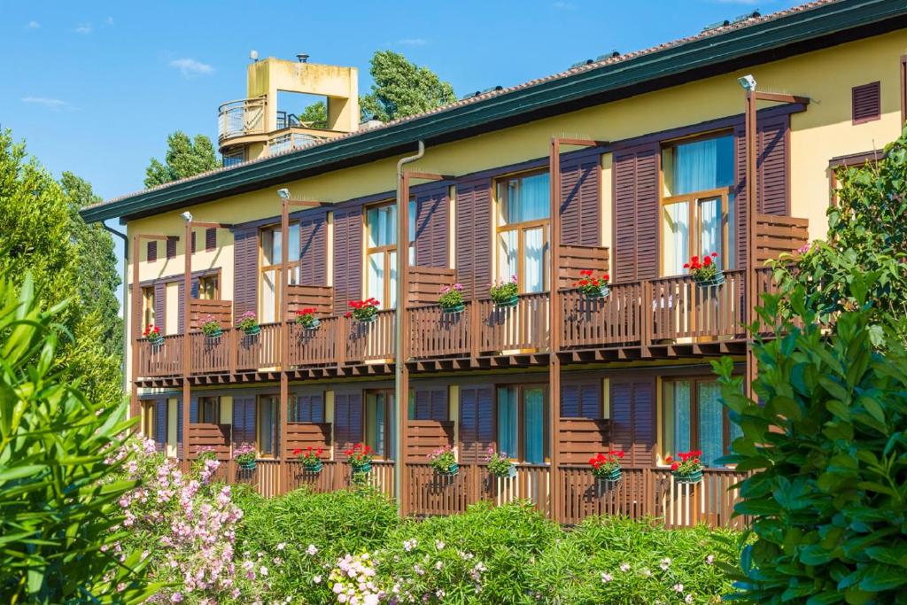 un edificio de apartamentos con balcones de madera y macetas de flores en Hotel Golf Inn, en Lignano Sabbiadoro