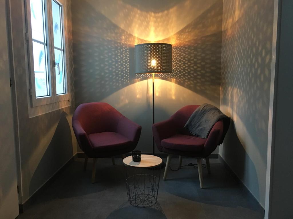 two chairs and a table in a room with a lamp at Bleu Bambou in Hauterive