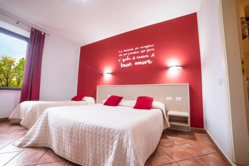 2 camas en una habitación con una pared roja en Hotel Ristorante Moderno, en SantʼAntìoco