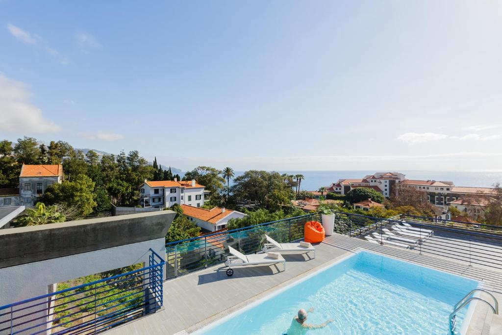 a person swimming in a swimming pool on top of a building at Terrace Mar Suite Hotel in Funchal