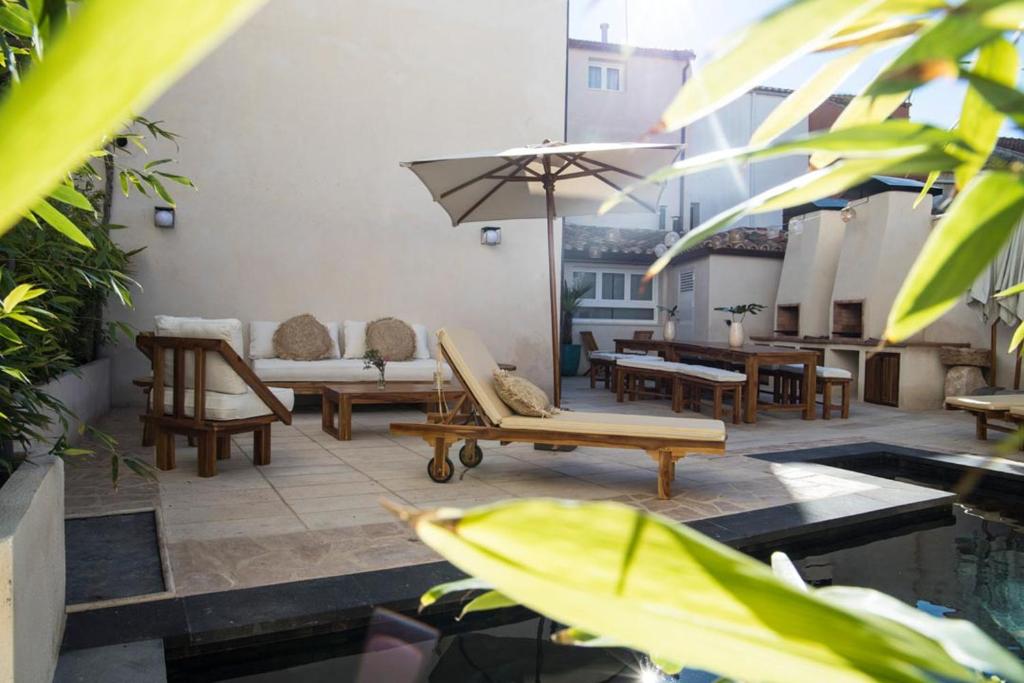 un patio con sillas, mesas y una sombrilla en Arco de la Villa en Mondéjar