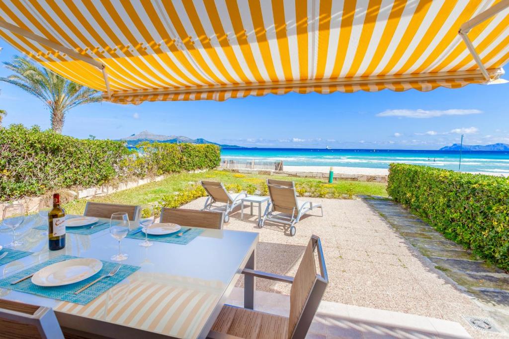 a dining table and chairs with a view of the beach at Beachfront Villa Socias Playa in Playa de Muro