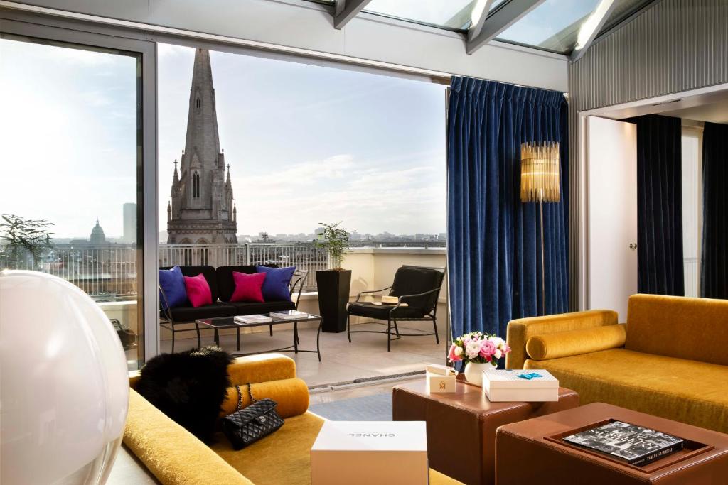 a living room filled with furniture and a large window at Hôtel De Sers Champs Elysées Paris in Paris