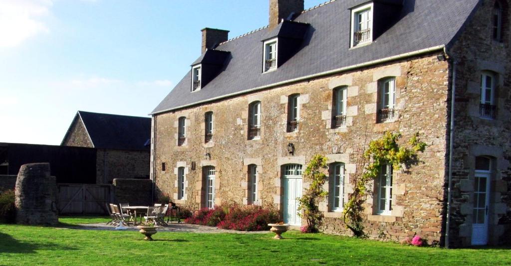 蓬托尔松La Vieille Foulonnière : Chambres d'hôtes & Permaculture的一座大砖砌建筑,在院子里设有桌子