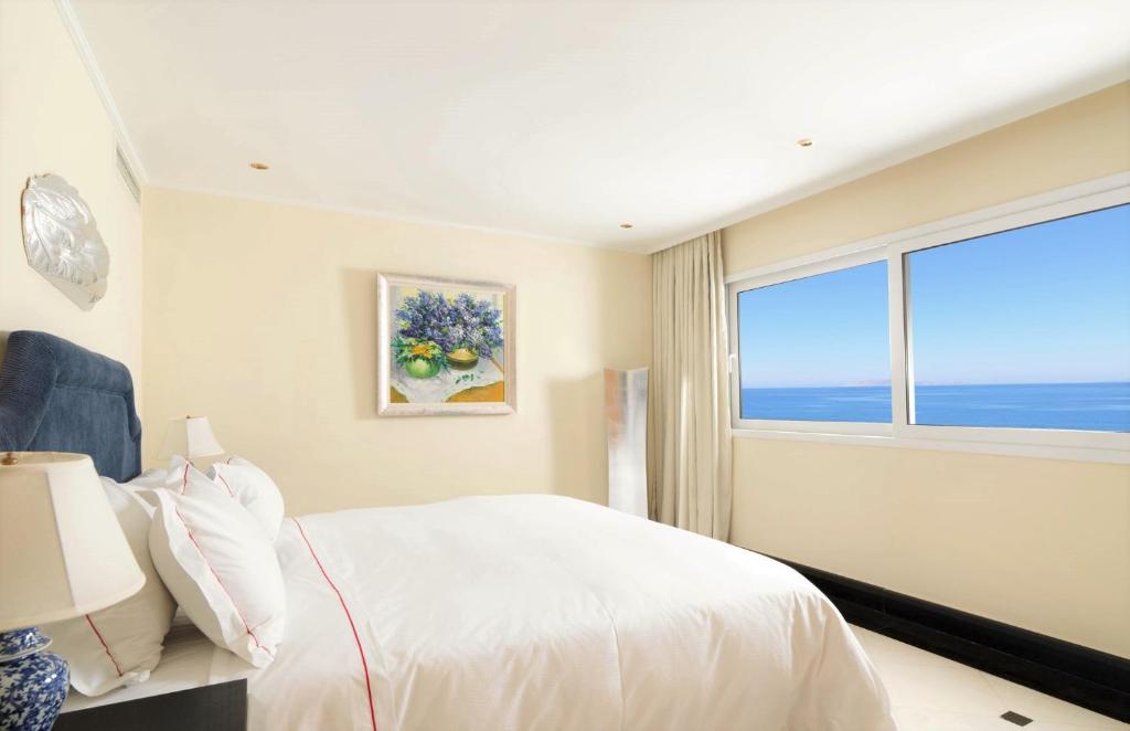 a bedroom with a white bed and a large window at Out Of The Blue Resort & Spa in Agia Pelagia