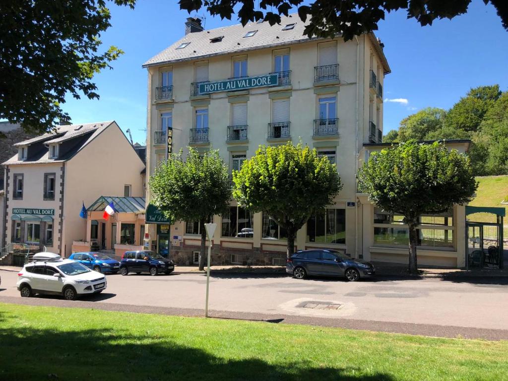 duży budynek z samochodami zaparkowanymi na parkingu w obiekcie Hotel Au Val Doré w mieście Bourboule