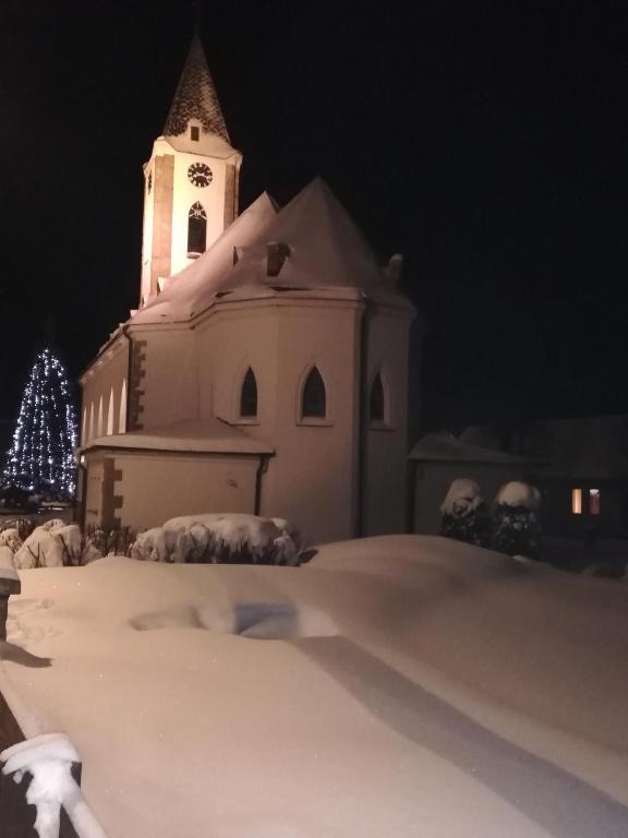 a church with a clock tower in the snow at night at Apartmány Grobarčík in Zuberec