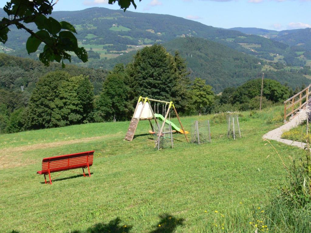 a red bench in a field with a playground at Gîte la Sapinière in Labaroche
