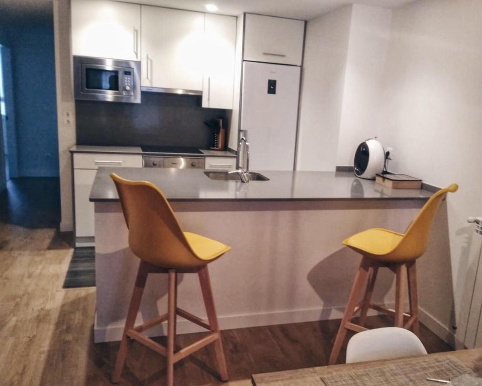 a kitchen with two yellow chairs and a counter at Apartamento Erdi Kale in Azpeitia