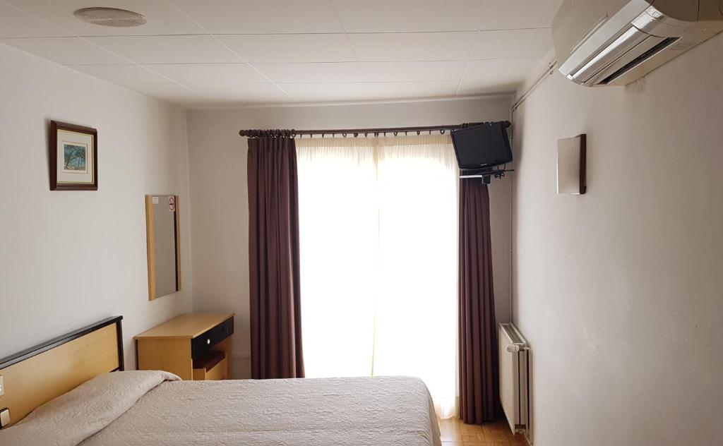 a bedroom with a bed and a large window at Hotel La Cala in Roses