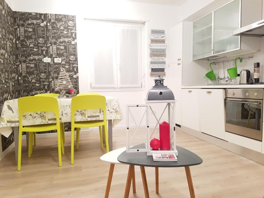 une cuisine blanche avec des chaises jaunes et une table dans l'établissement le stanze del Trenino Rosso, à Tirano
