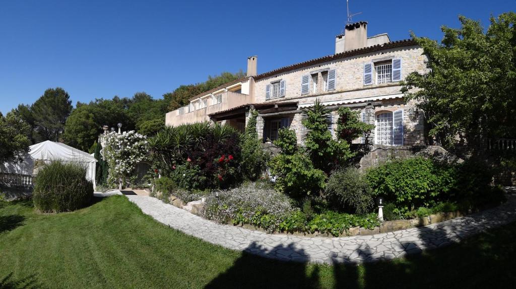 una gran casa de piedra con un jardín delante de ella en Domaine du Paradis des Oiseaux, en Mougins