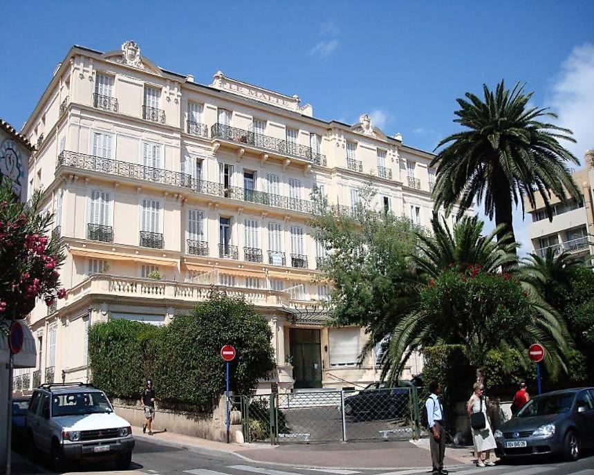 - un grand bâtiment blanc avec des personnes marchant devant dans l'établissement Le Malte, à Menton