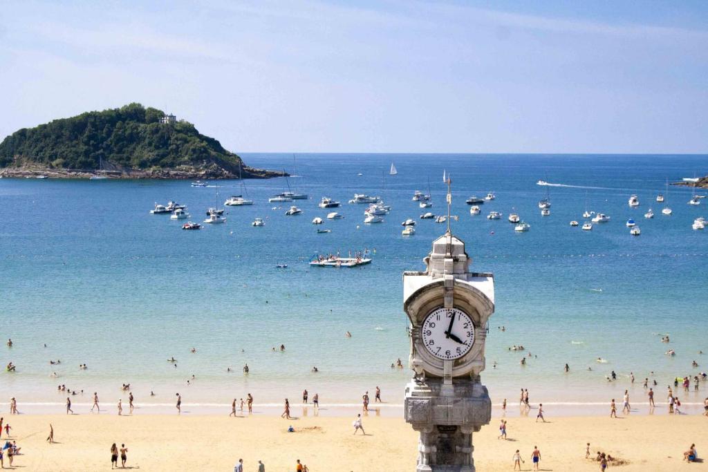 wieża zegarowa na plaży z tłumem ludzi w obiekcie The Rentals Collection | BellaVista w mieście San Sebastián
