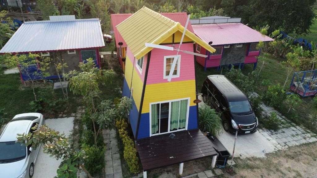 een kleurrijk huis met een busje ervoor geparkeerd bij รุ่งฟ้า ฟาร์มสเตย์ in Ban Sap Phrik