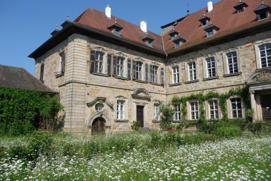 an old building with a field of flowers in front of it at Ferienzimmer im Schloss Burgpreppach in Burgpreppach